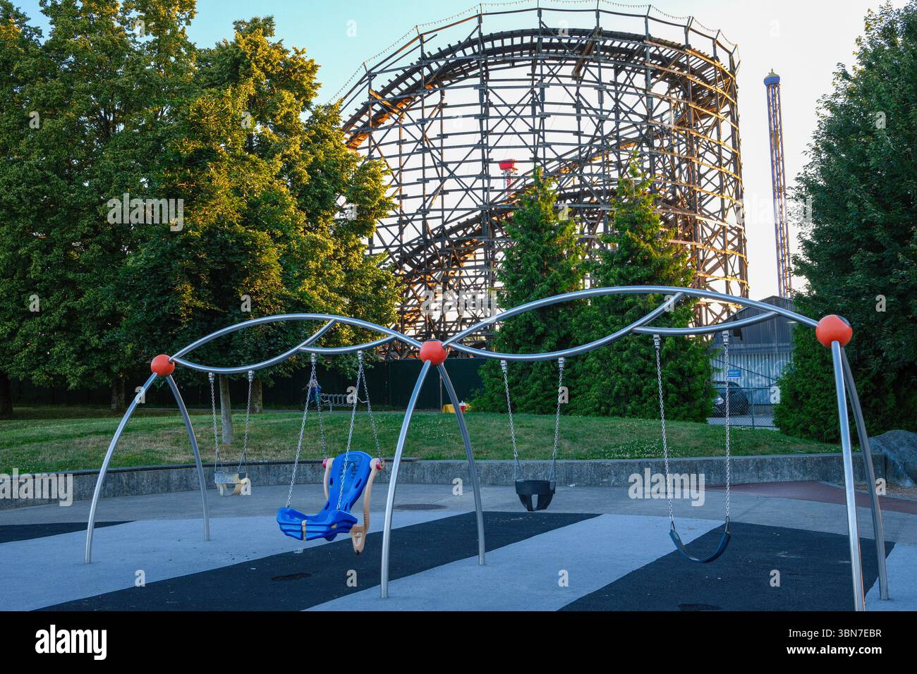 The Coaster, a 1958 wooden rollercoaster behind a swingset at Playland, on the Pacific National Exhibition grounds at Hastings Park in Vancouver, BC. Stock Photo