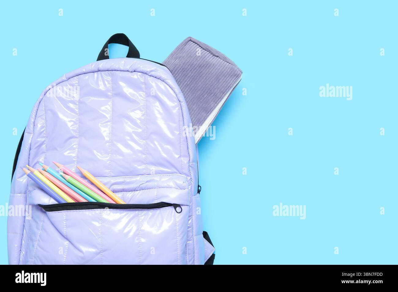 Lilac school backpack with stationery on blue background Stock Photo