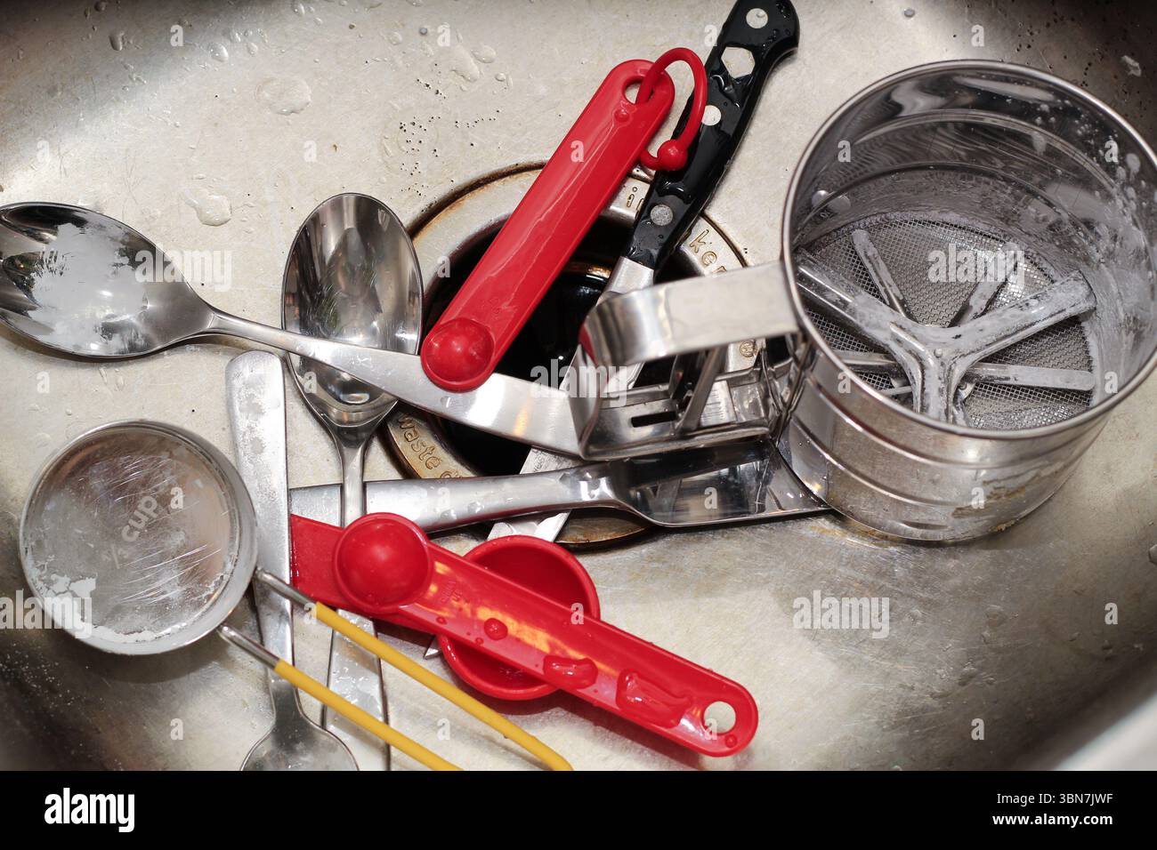 Baking utensils and measuring cups, spoons in kitchen sink. Stock Photo