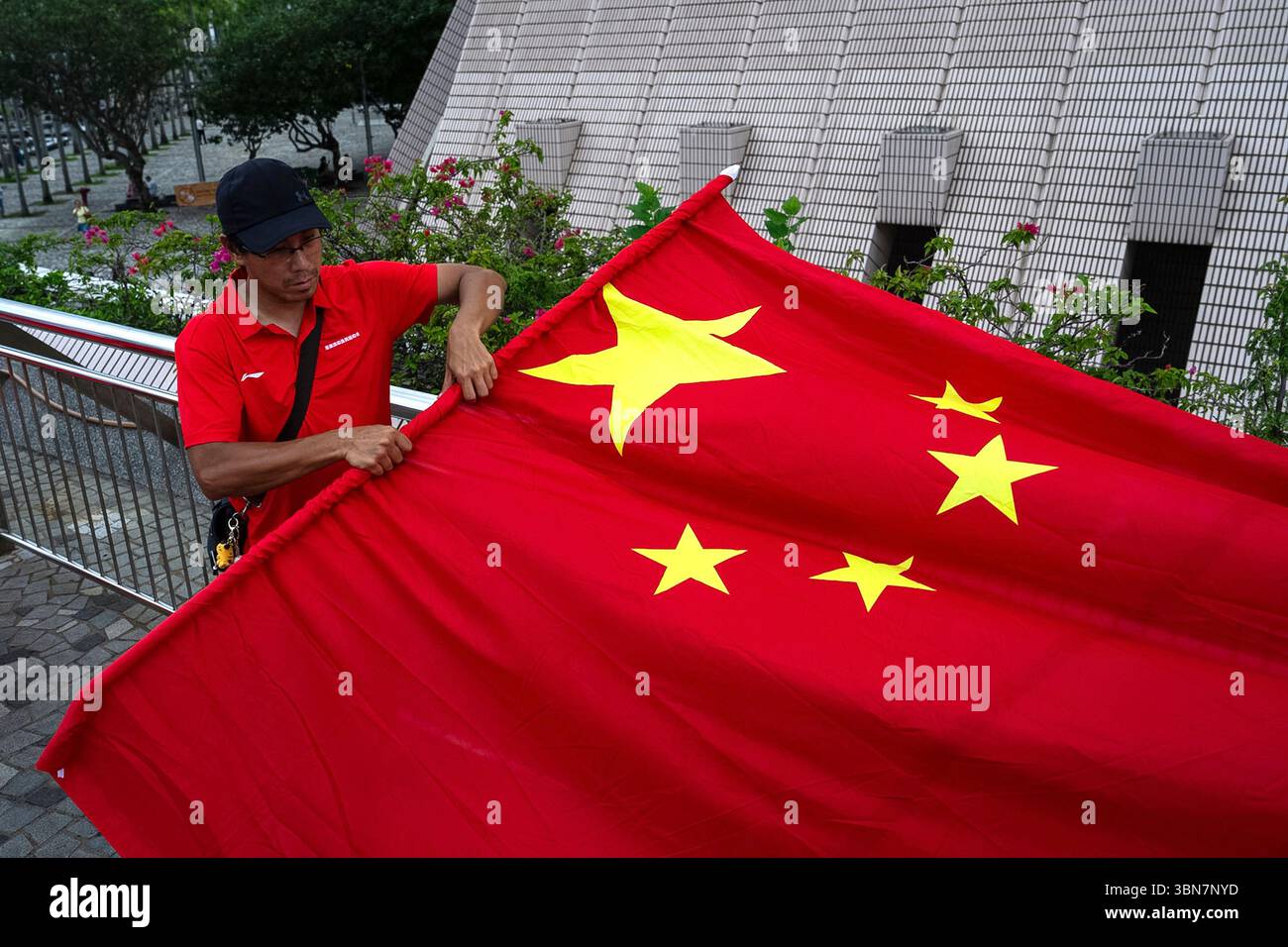 A pro-Beijing supporter folds a Chinese flag following a ceremony to ...