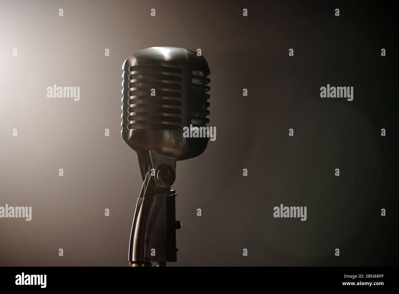Vintage microphone standing alone on stage under dramatic lighting, symbolizing jazz musicians preparing for live performance, classic microphone design evoking musical nostalgia Stock Photo