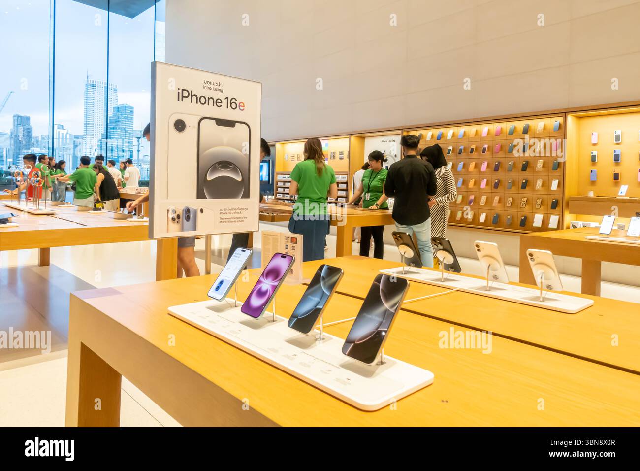 Apple store displays iPhones 16 on tables with customers and employees browsing, Iconsiam mall, Bangkok Thailand Stock Photo