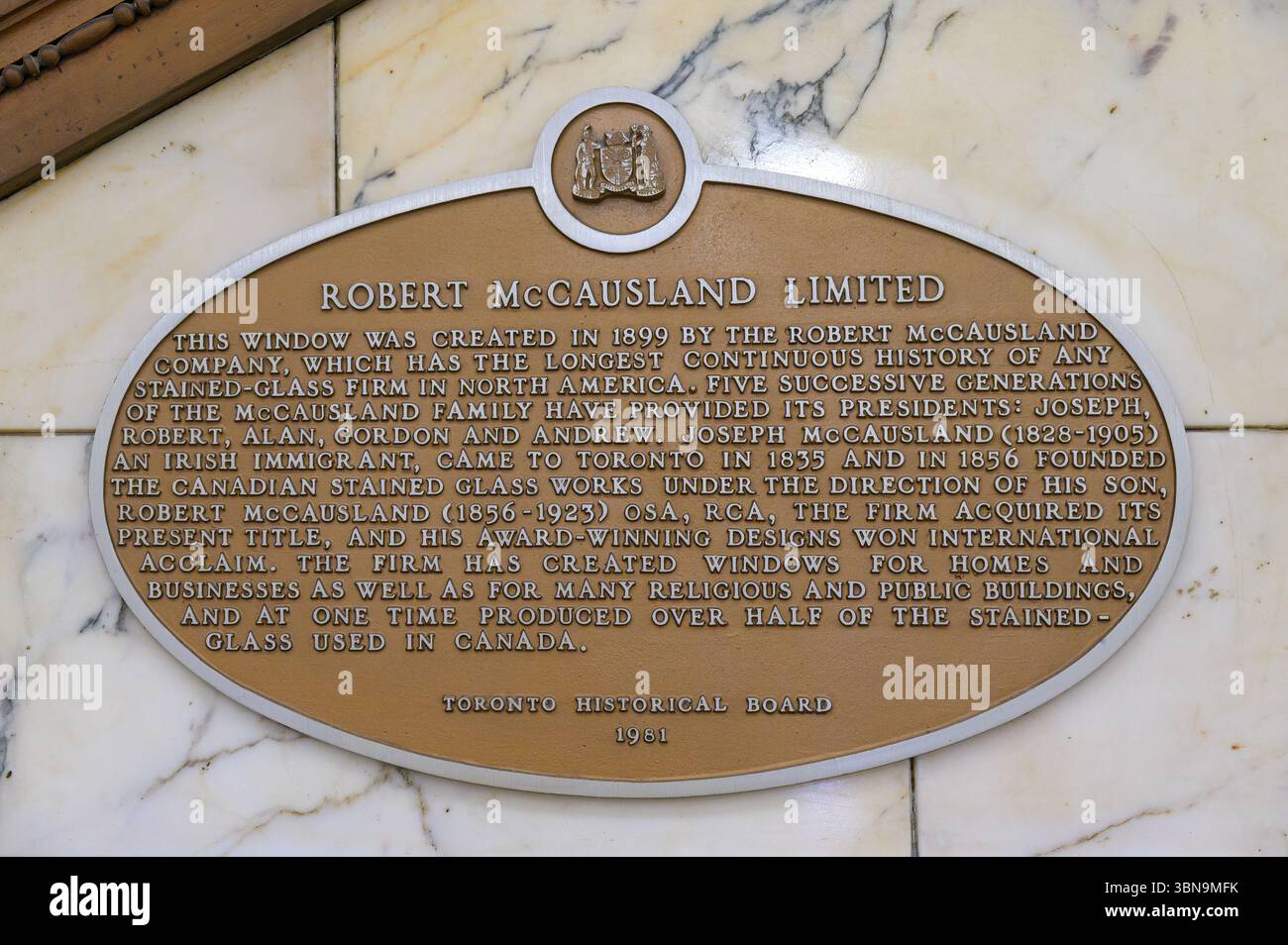 A plaque mounted on a marble wall inside Old City Hall commemorates Robert McCausland Limited, detailing the firmís stained glass legacy in North Amer Stock Photo