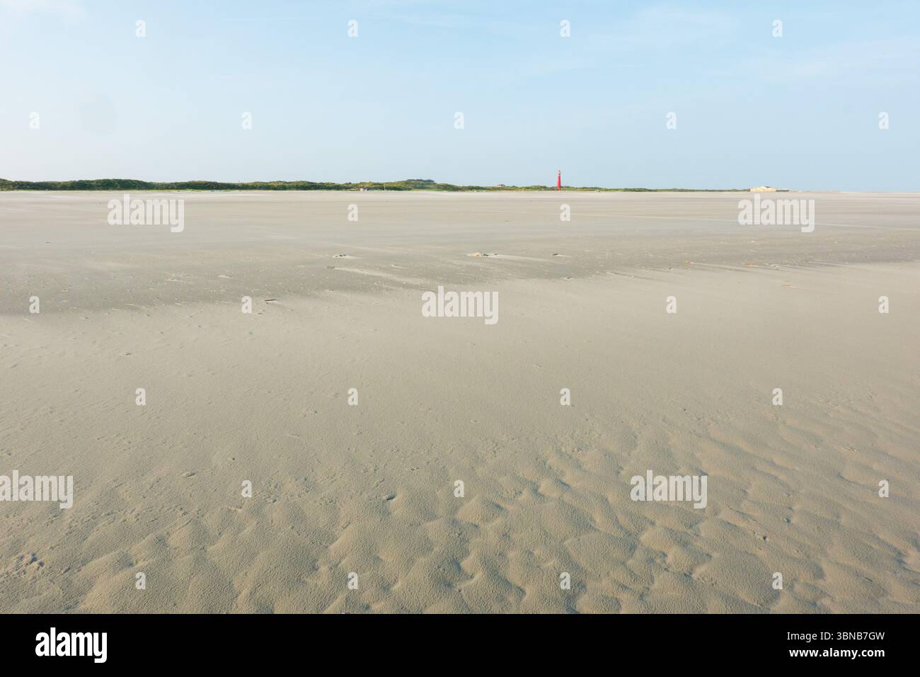 Vast, wide, empty beach, a red lighthouse in the far distance Stock Photo