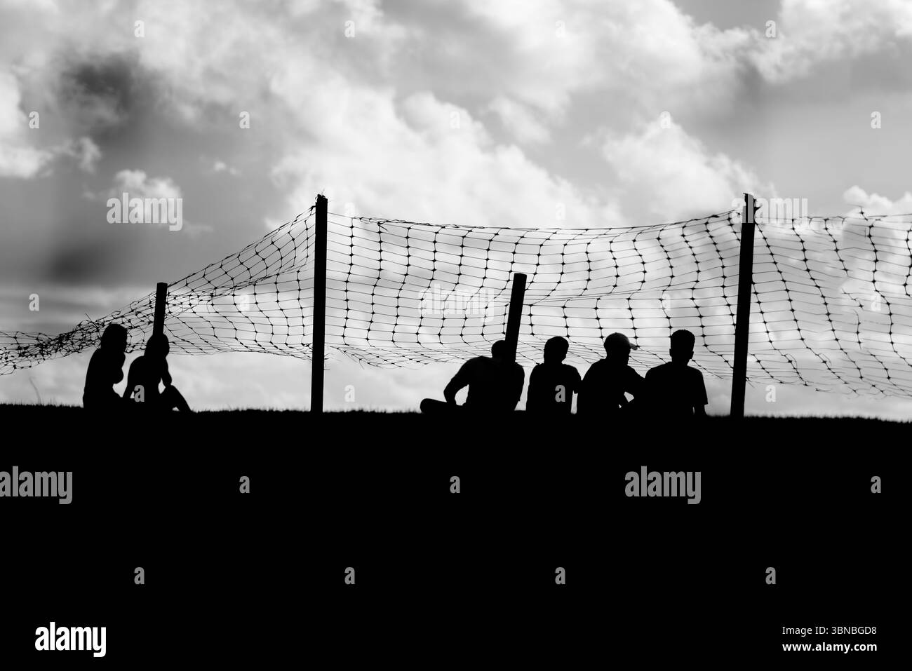 Black and white photo with silhouettes of unidentified people enjoying the beautiful sunset. Late afternoon. People traveling. Stock Photo