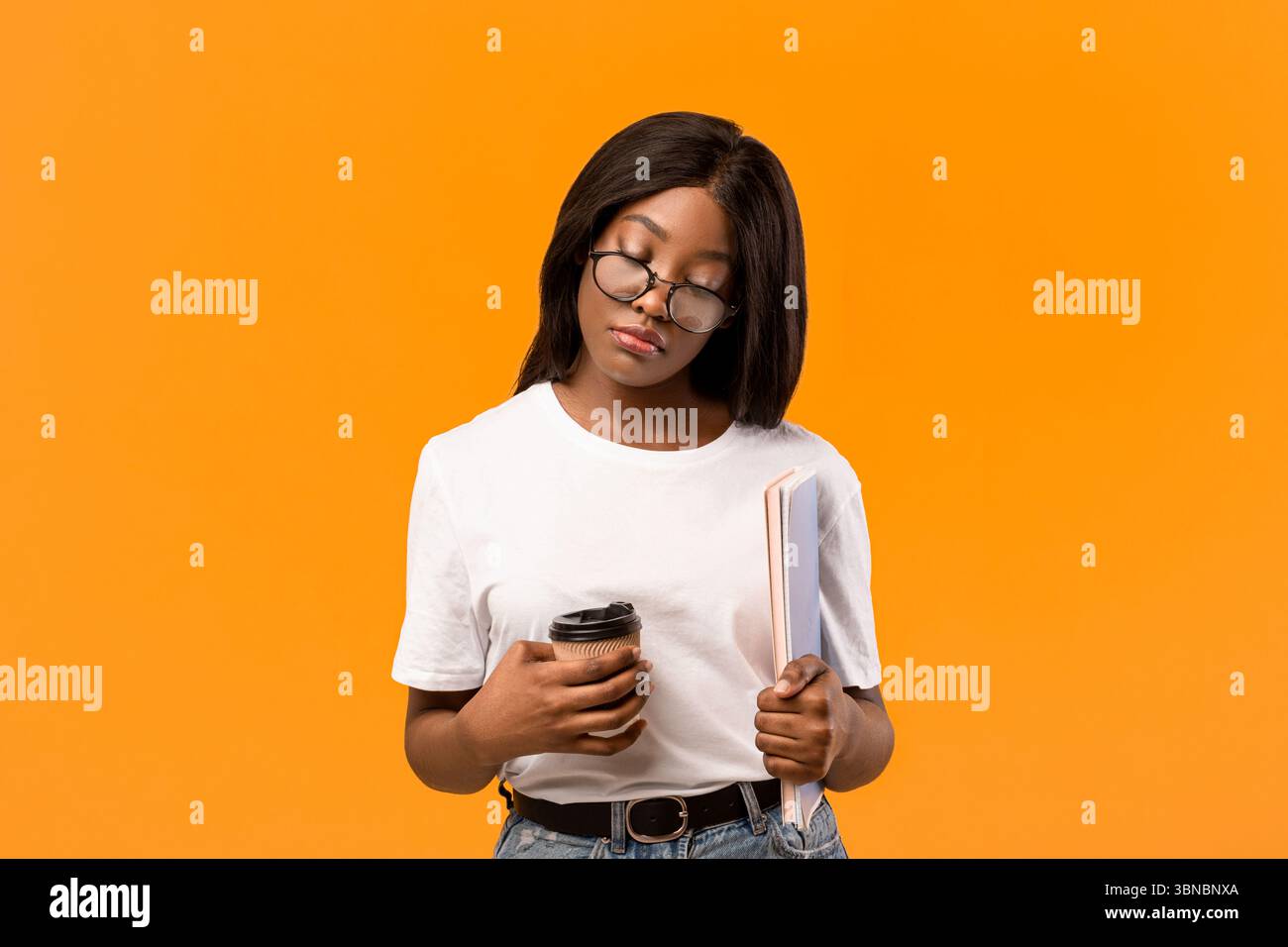 Tired black lady student with books sleeping on orange Stock Photo