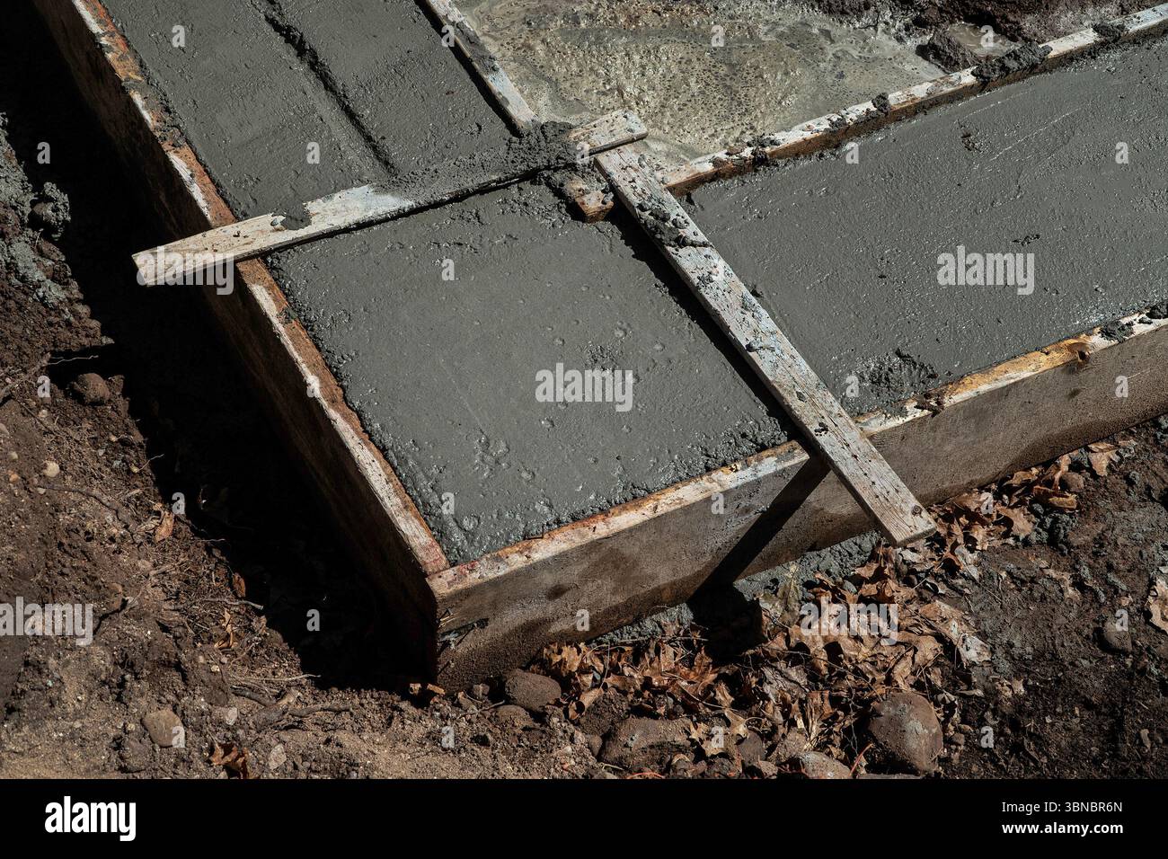 Freshly poured concrete foundation slab within wooden formwork. The concrete is in the early stages of setting. Stock Photo