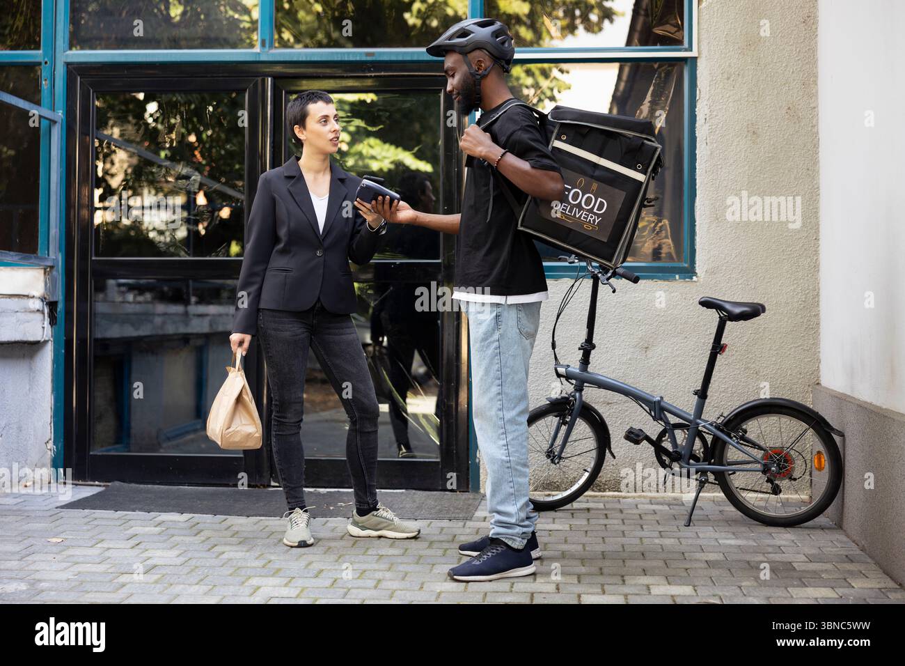 Black delivery person completes a food transaction as customer pays ...
