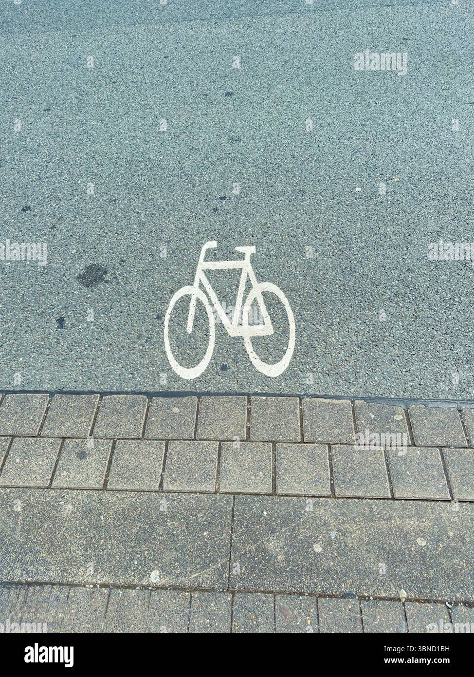 A clear white bicycle symbol painted on an asphalt surface, indicating ...