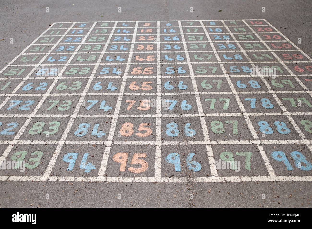 Hundred square painted on tarmac playground 100 square numeracy numbers counting count children learning to count Stock Photo