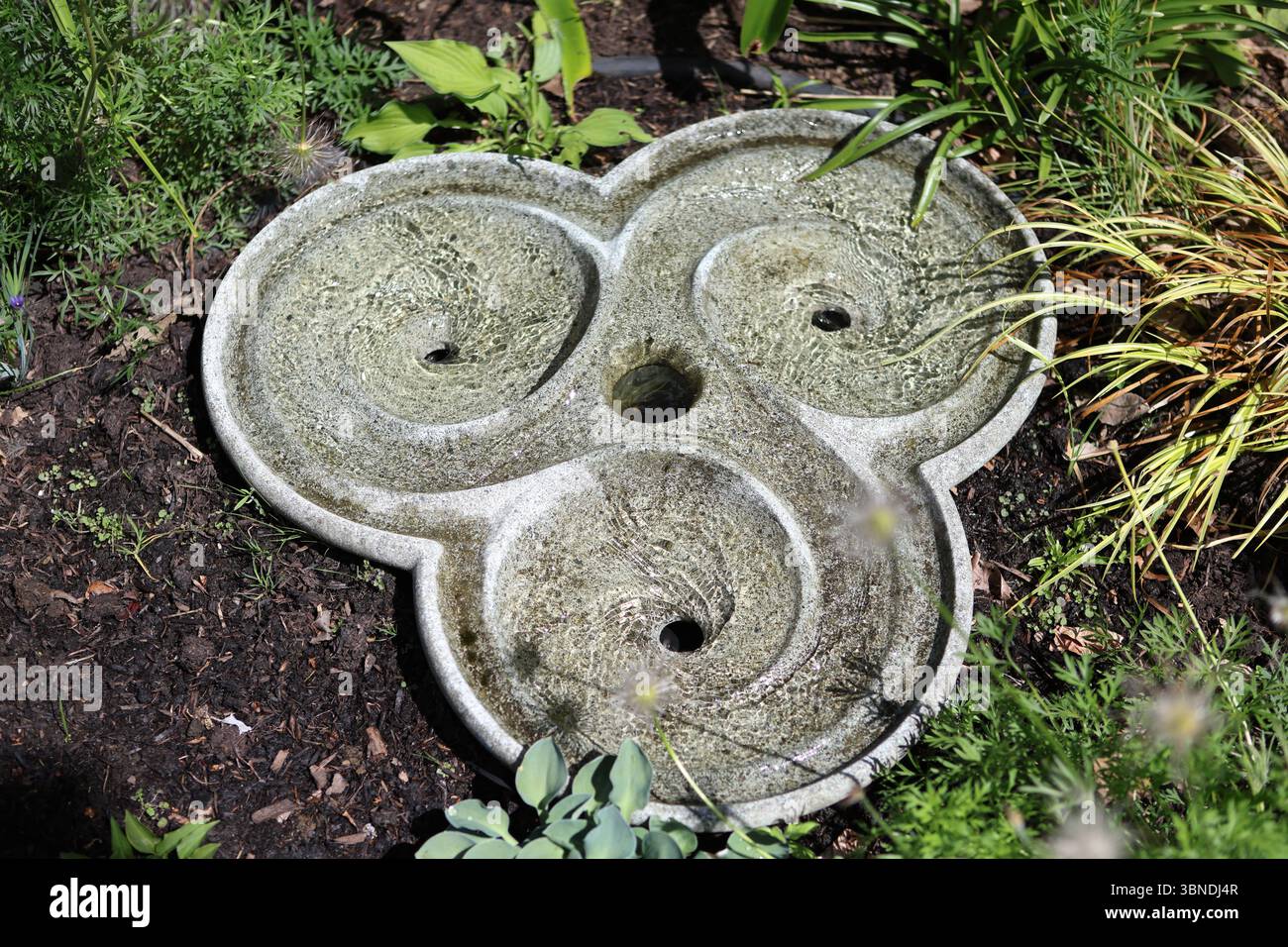 Water feature in garden swirls water swirling in three swirls Stock Photo