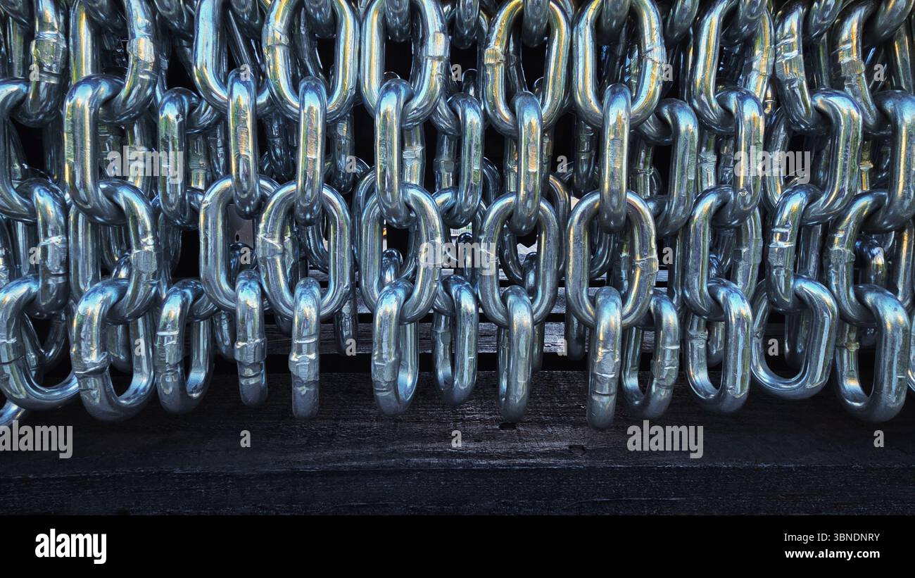 A row of intertwined shiny metal chains, showcasing their strength and industrial aesthetic in a close-up view. - Smartphone Captured Stock Image