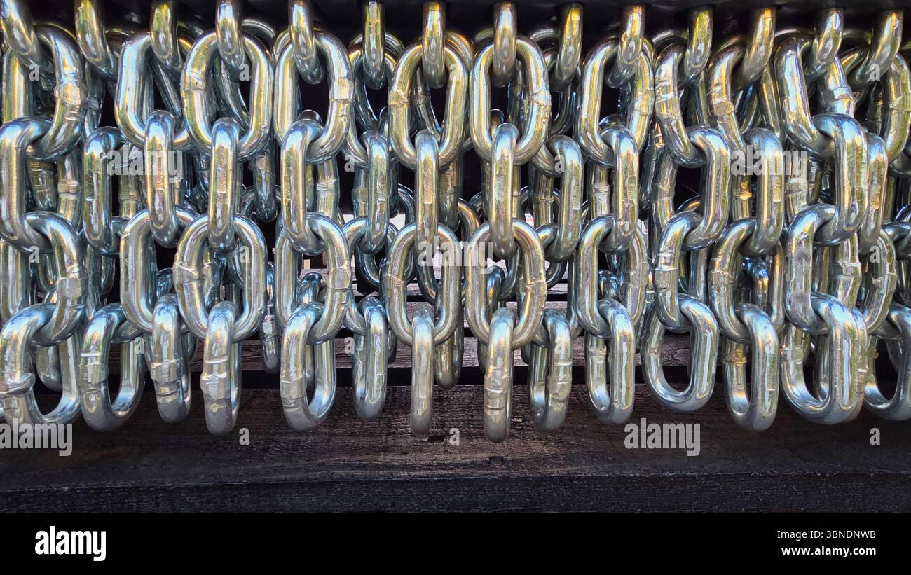 A row of intertwined shiny metal chains, showcasing their strength and industrial aesthetic in a close-up view. - Smartphone Captured Stock Image