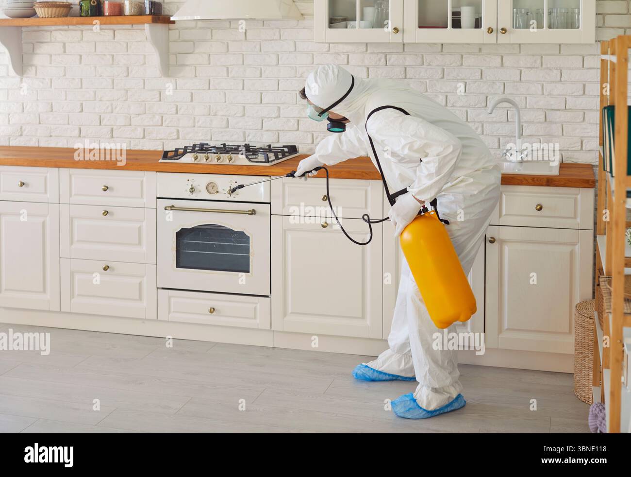 Man worker wearing white uniform and protective mask spraying insecticide chemical  Stock Photo