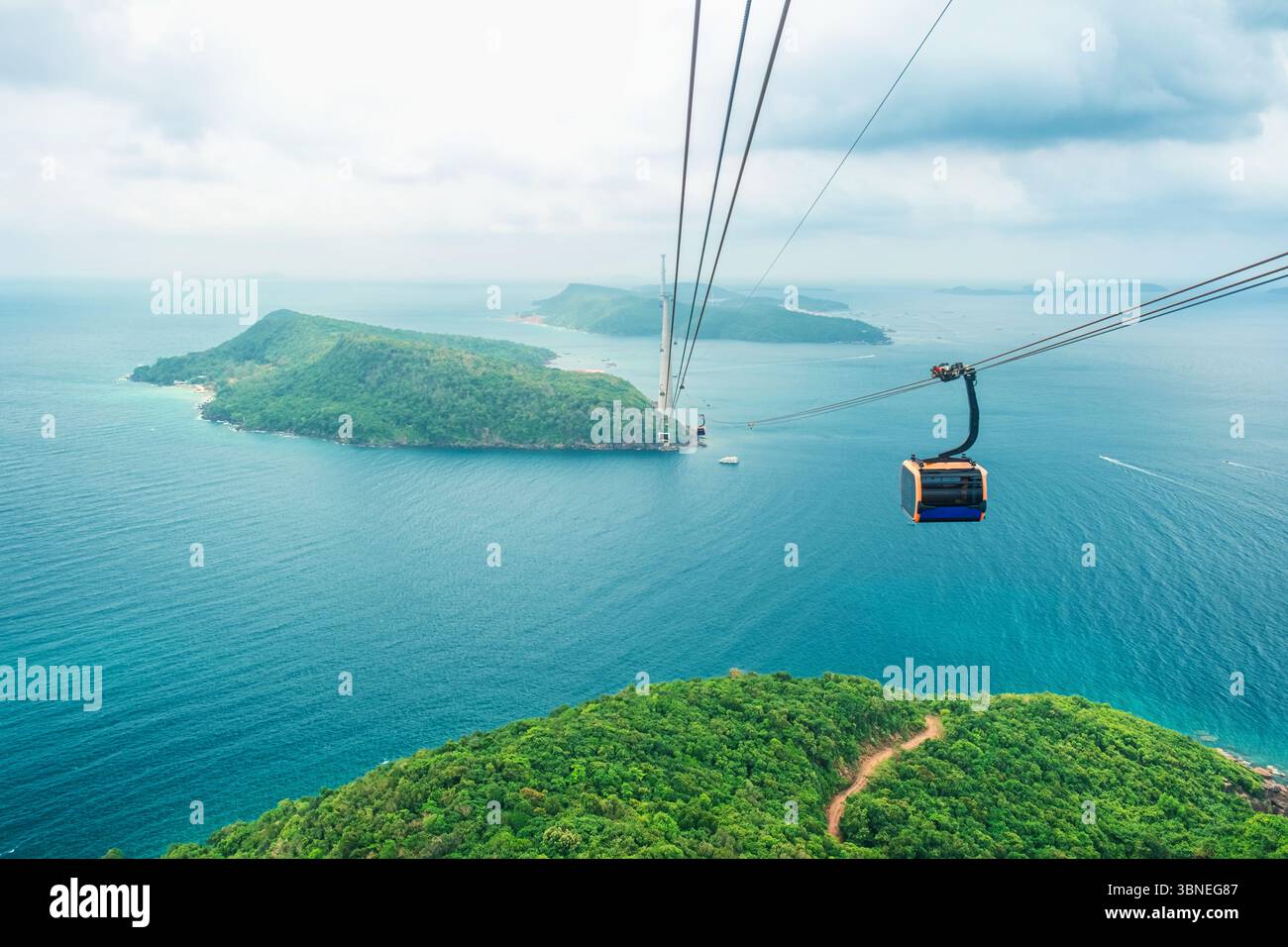 Cable car cabin gliding over turquoise sea and green tropical island ...