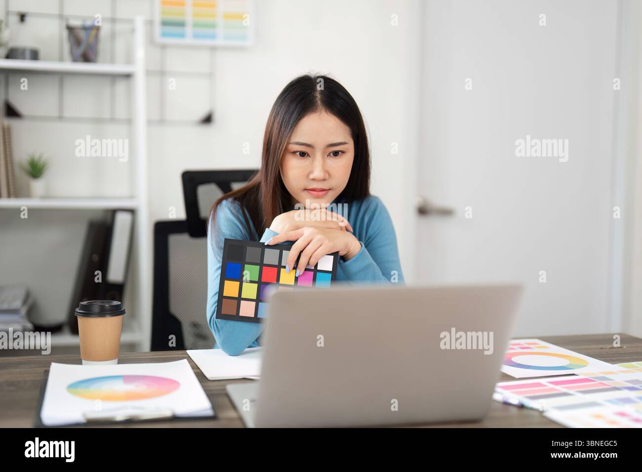 Color Theory and Design Choices. A woman analyzing color palettes on her laptop, immersed in a creative workflow. Stock Photo