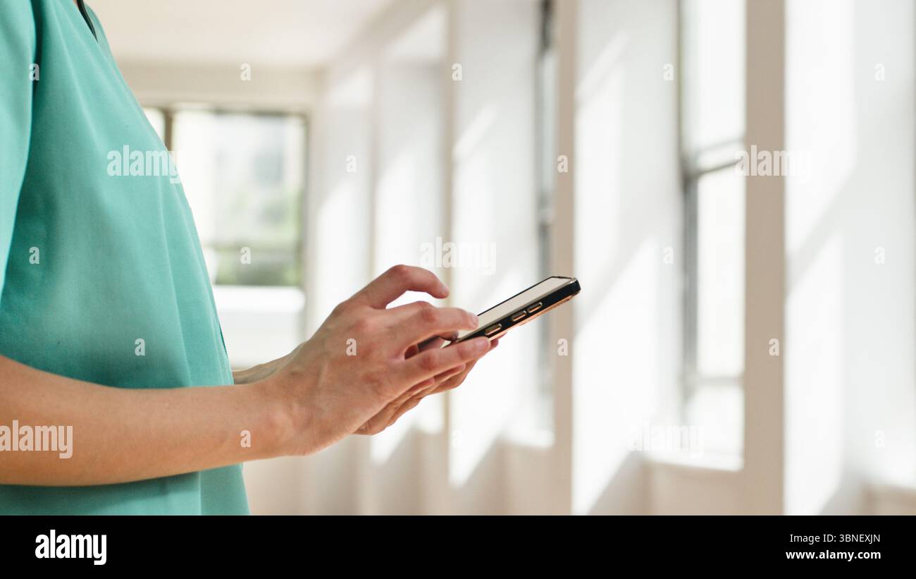 Medical Professional Utilizing Smartphone in Well-Lit Modern Interior Stock Photo
