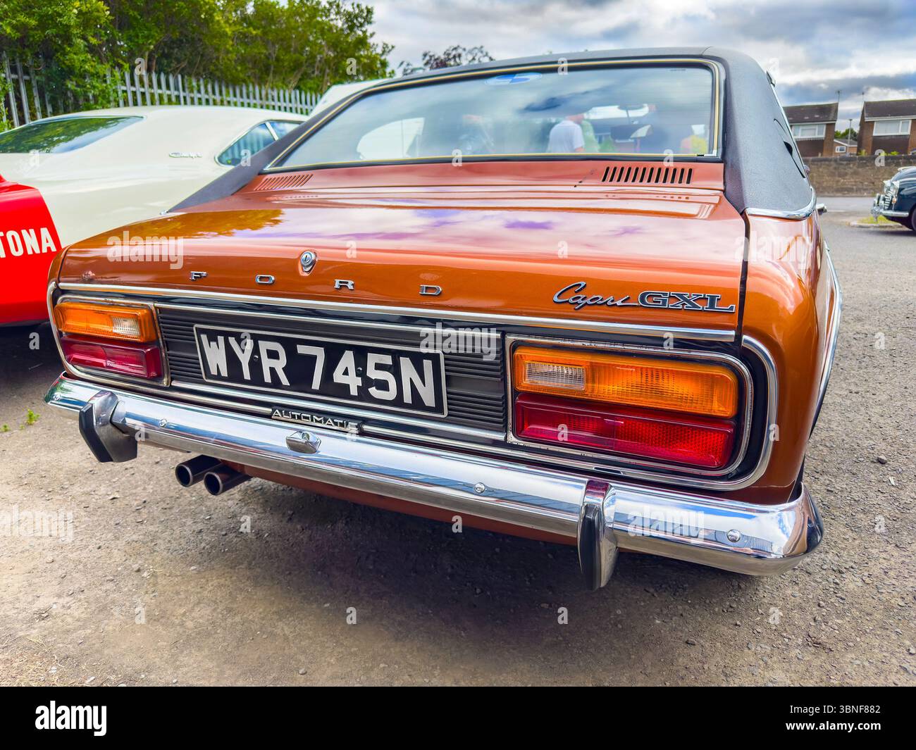 Rear view of a brown vintage Ford Capri GXL with a UK license plate in an outdoor setting, showcasing its classic design and distinct features - Smartphone Captured Stock Image