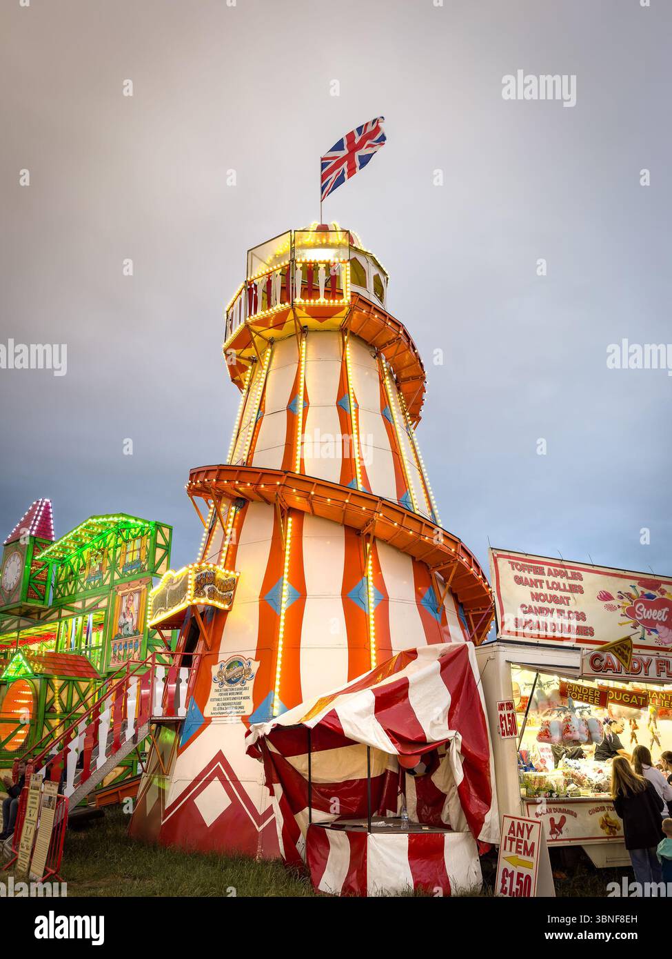 People at newcastle fun fair with a candy shop and a vintage helter-skelter ride during twilight The Hoppings town moor newcastle - Smartphone Captured Stock Image