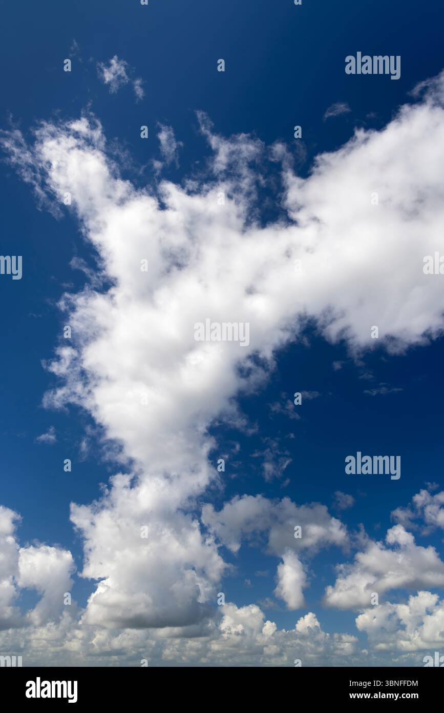 White clouds float across a vibrant blue sky Stock Photo