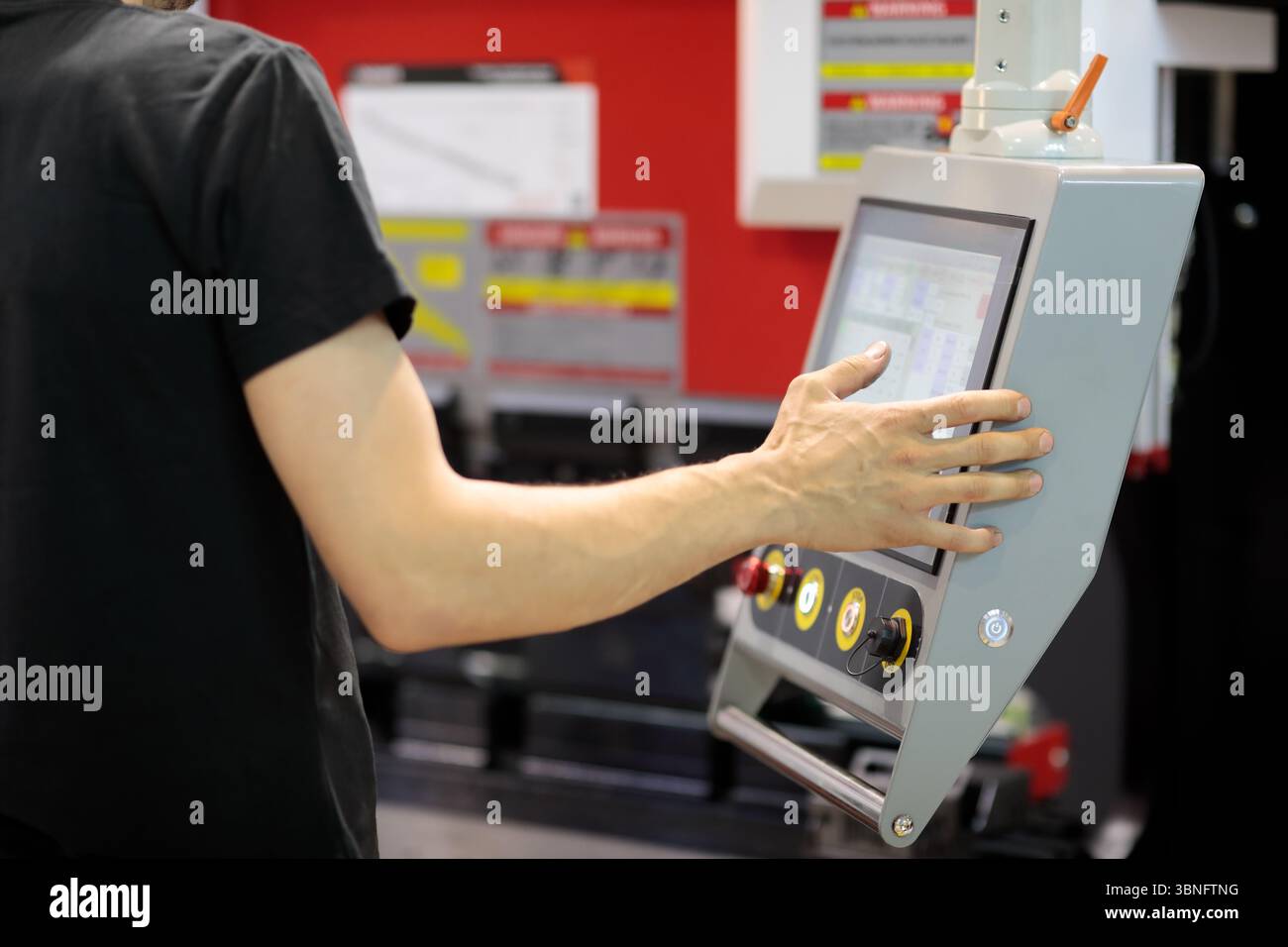 Operator programming hydraulic CNC press brake machine. Selective focus. Stock Photo