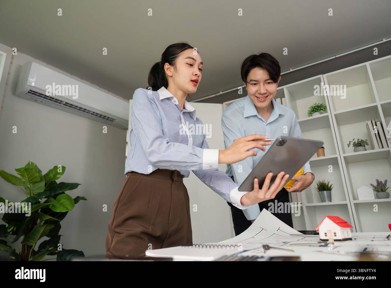 Digital Collaboration and Presentation. Team members sharing ideas using a tablet in a modern workspace. Stock Photo