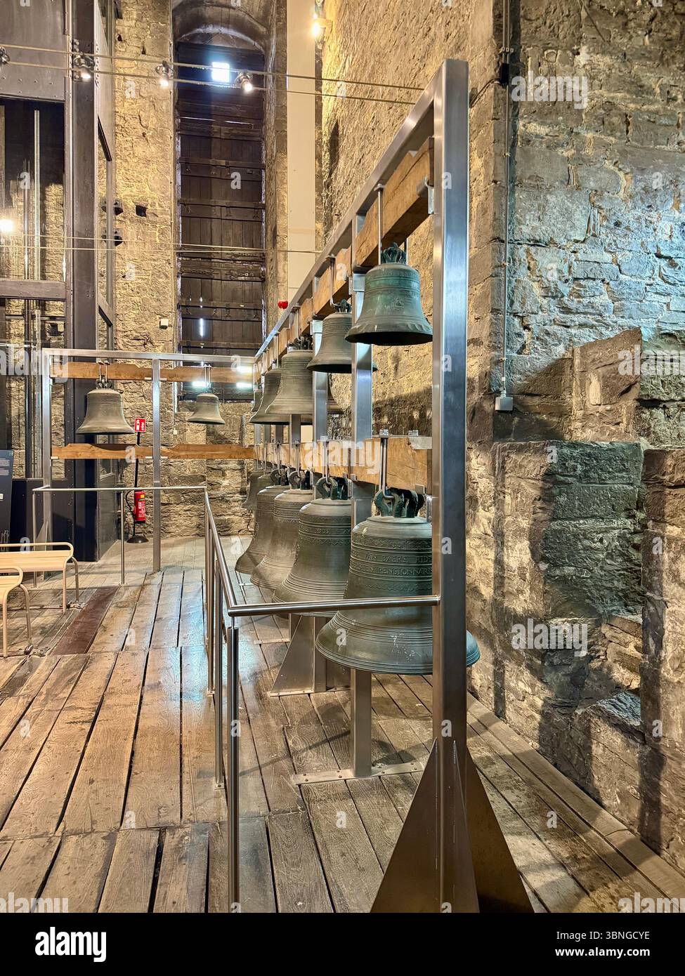 Row of historic tower bells mounted on a metal display frame inside the Belfry of Ghent (Belfort van Gent) museum, Belgium. - Smartphone Captured Stock Image Row of historic tower bells mounted on a metal display frame inside the Belfry of Ghent (Belfort van Gent) museum, Belgium. - Smartphone Captured Stock Image