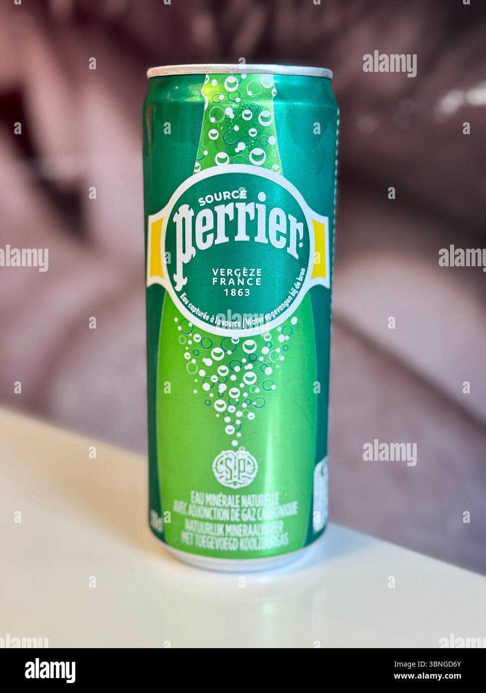 Slim can of Perrier natural sparkling mineral water against a soft-focus background. - Smartphone Captured Stock Image