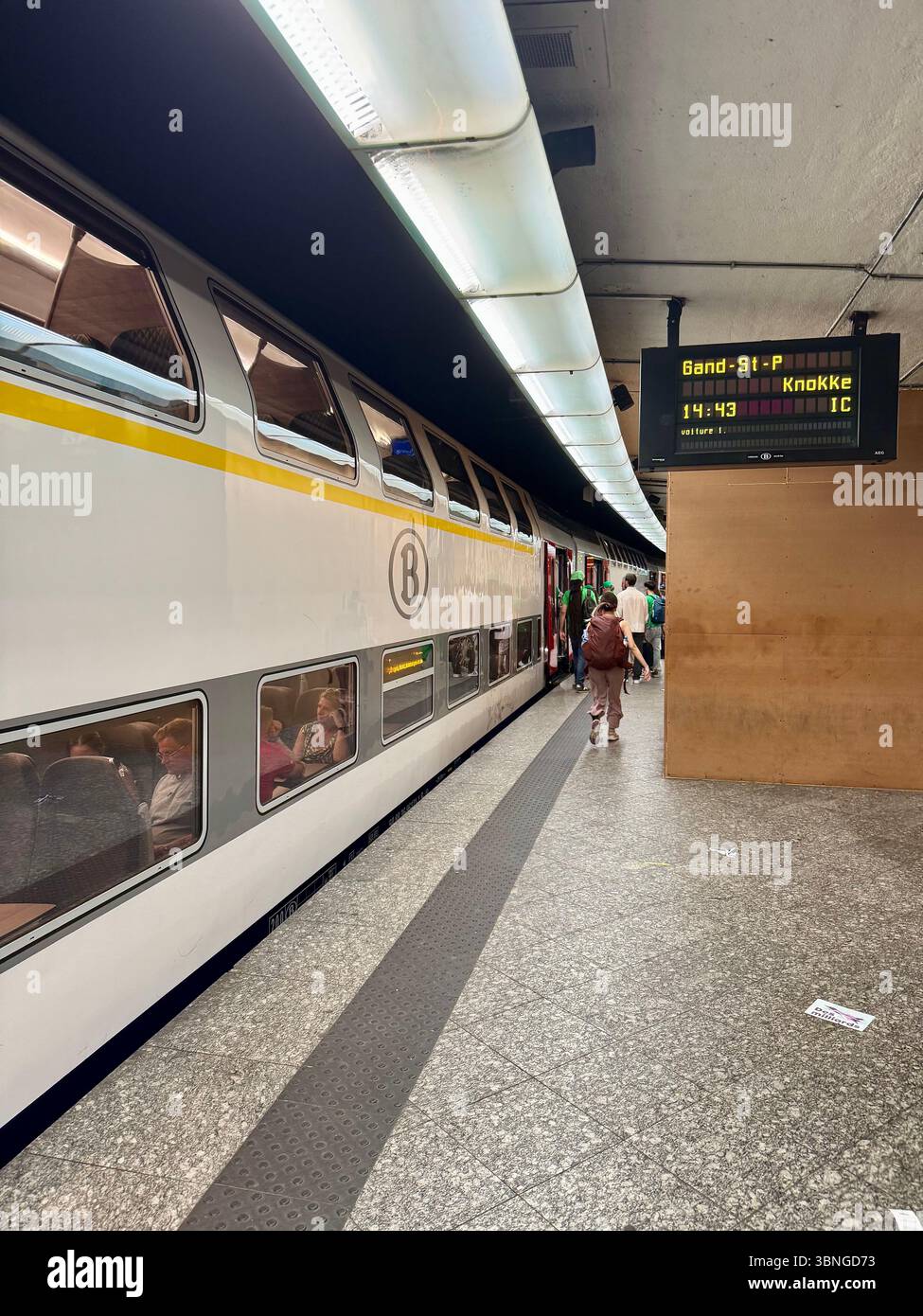 Double‑decker passenger train at a Belgian railway platform with digital departure board. - Smartphone Captured Stock Image