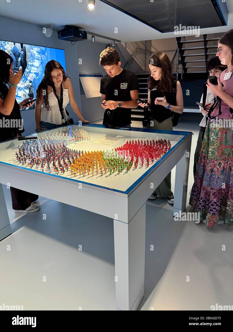 Visitors interact with a colorful exhibit of miniature figurines at the Parlamentarium museum in Brussels, Belgium. - Smartphone Captured Stock Image