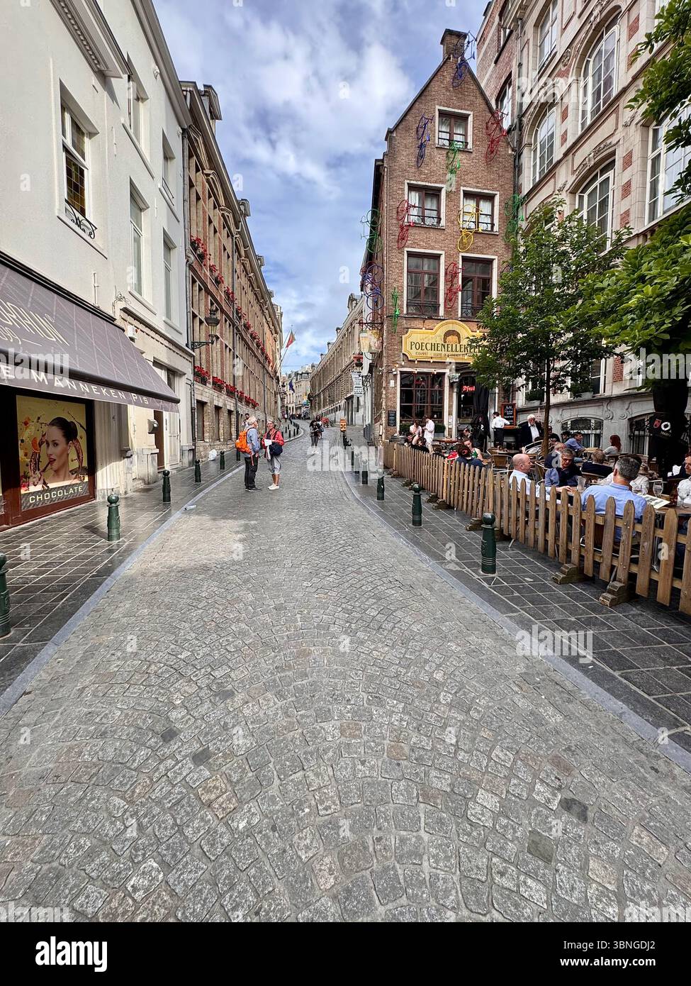 Narrow cobblestone street lined with cafés and historic façades in central Brussels, Belgium. - Smartphone Captured Stock Image