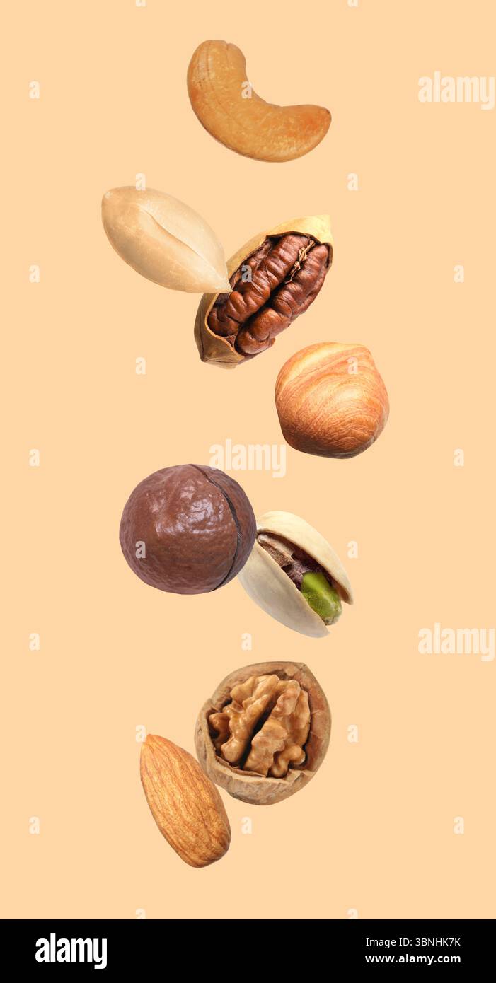 Peanut and other nuts falling on beige background Stock Photo