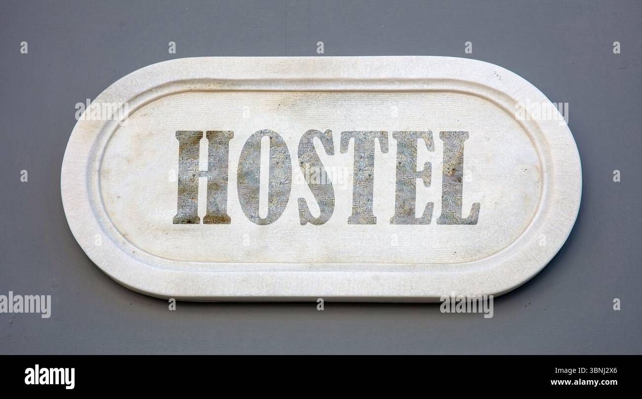 HOSTEL text marble sign on grey blue wall Stock Photo