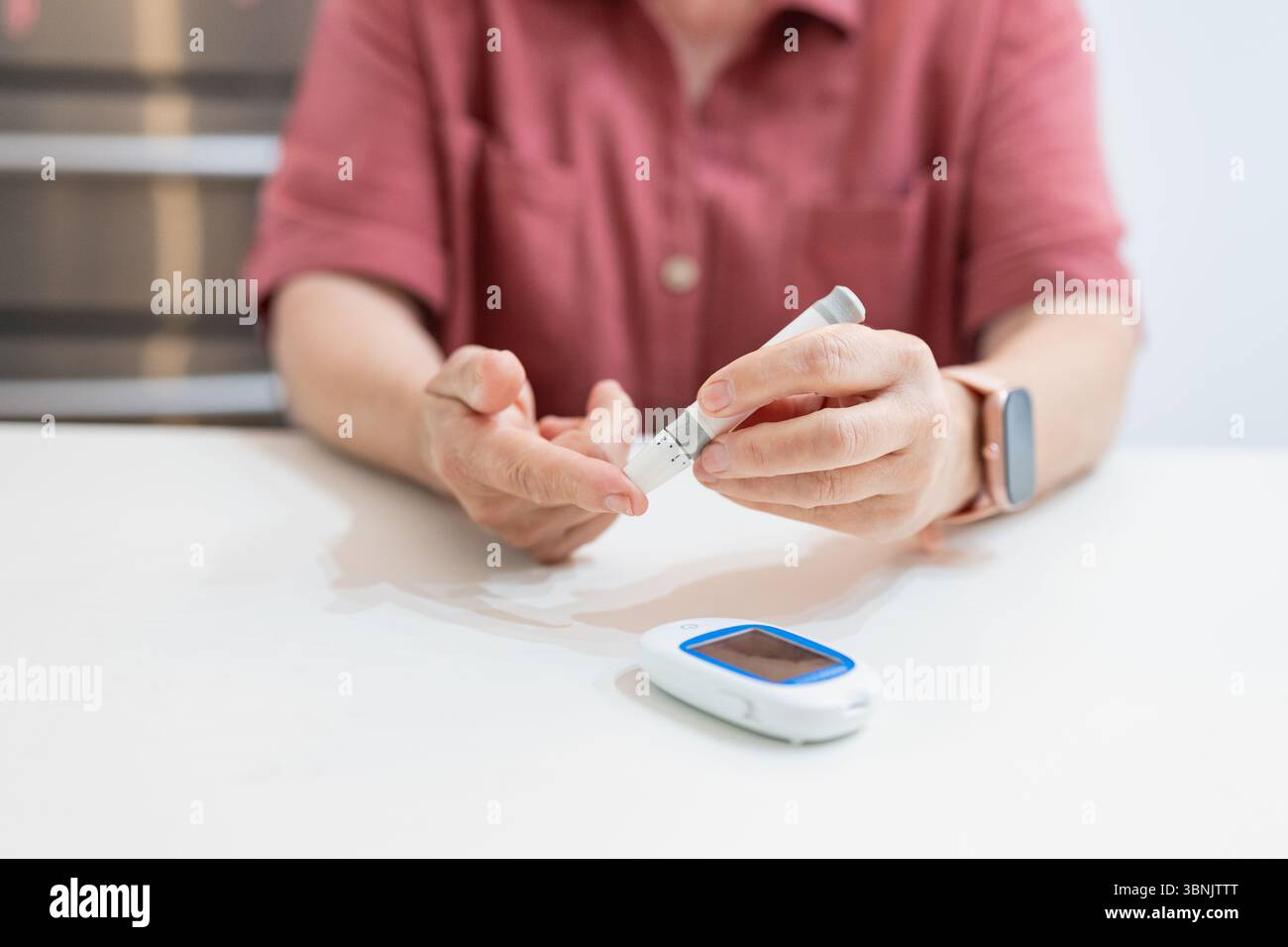 Cropped unrecognizable elderly woman checks her blood glucose at home, illustrating daily health management and self-care with a glucose meter on a wh Stock Photo