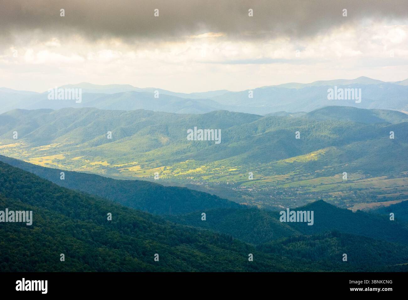 mountain landscape with green peak under storm sky. beautiful summer scenery of carpathian watershed ridge. scenic view of valley in dappled light. ou Stock Photo