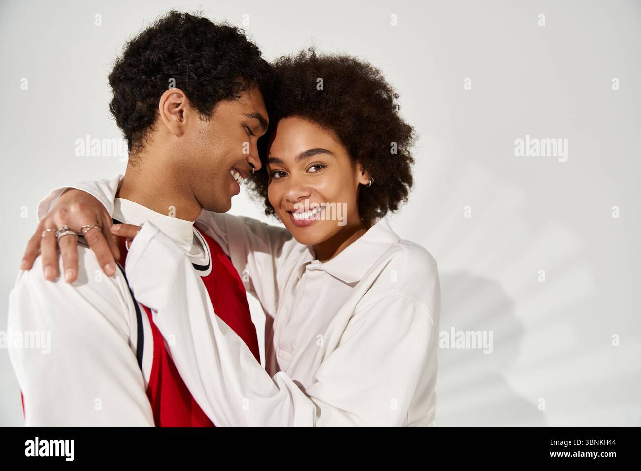 Stylish young couple embraces warmly, radiating love and happiness in their aesthetic attire. Stock Photo