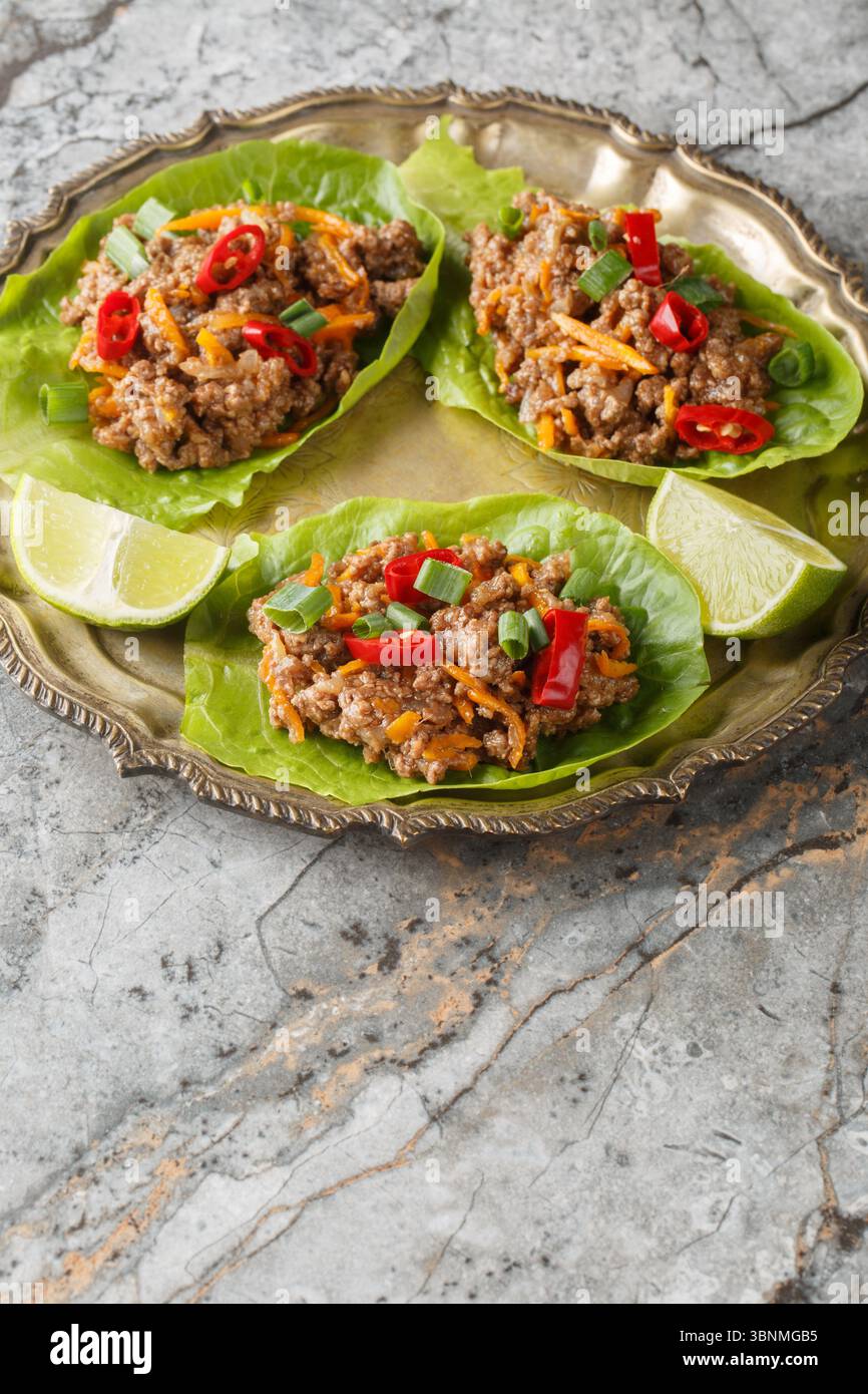 Juicy Thai Beef Lettuce Cups close-up on the plate on table. Vertical Stock Photo