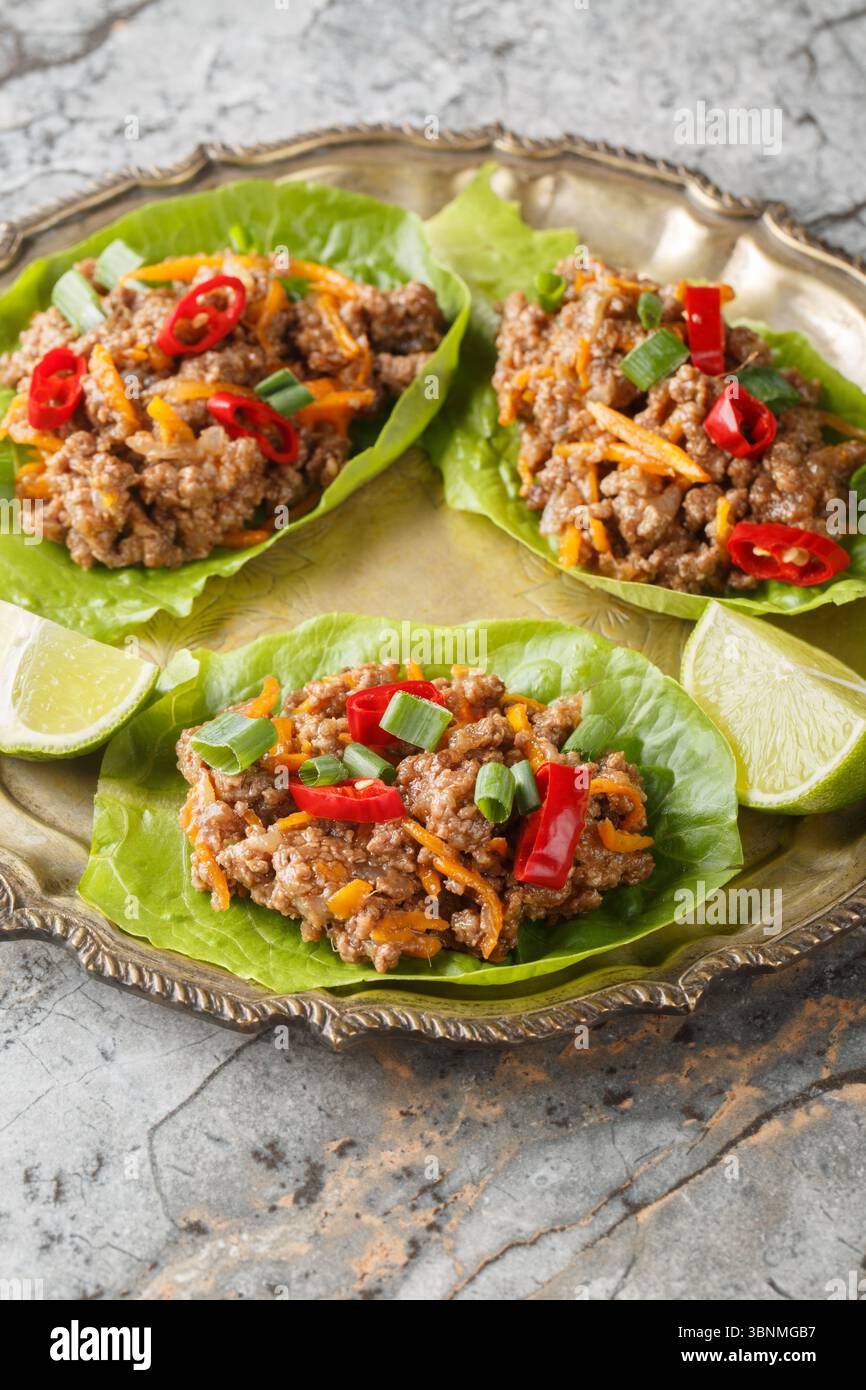 Beef cups or minced meat lettuce wraps on close-up on plate on table. Vertical Stock Photo