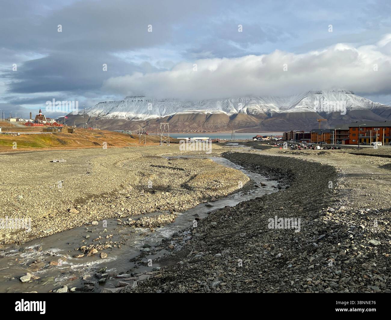 A beautiful view of mountains, a river, and buildings under the cloudy sky. Longyearbyen Svalbard - Smartphone Captured Stock Image