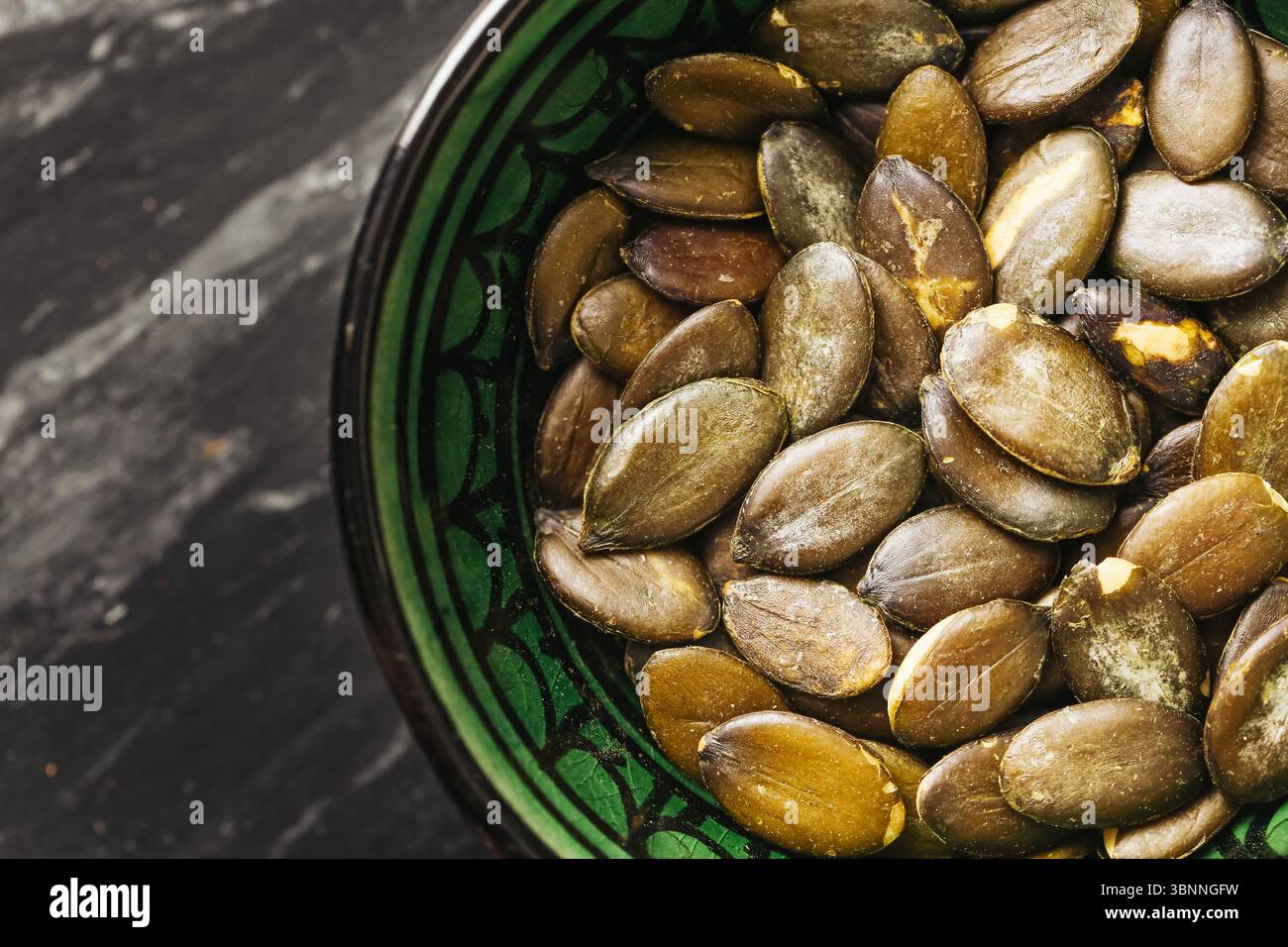 Pumpkin seeds in bowl. Close-up of green roasted snack. Healthy natural food. Source of protein and fiber. Vegan ingredient for salads or baking. Stock Photo