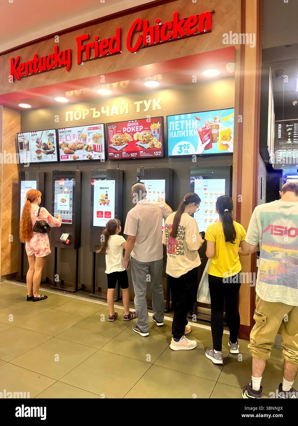 Customers at Kentucky Fried Chicken self-service kiosks in shopping mall in Sofia Bulgaria, Eastern Europe, Balkans, EU - Smartphone Captured Stock Image