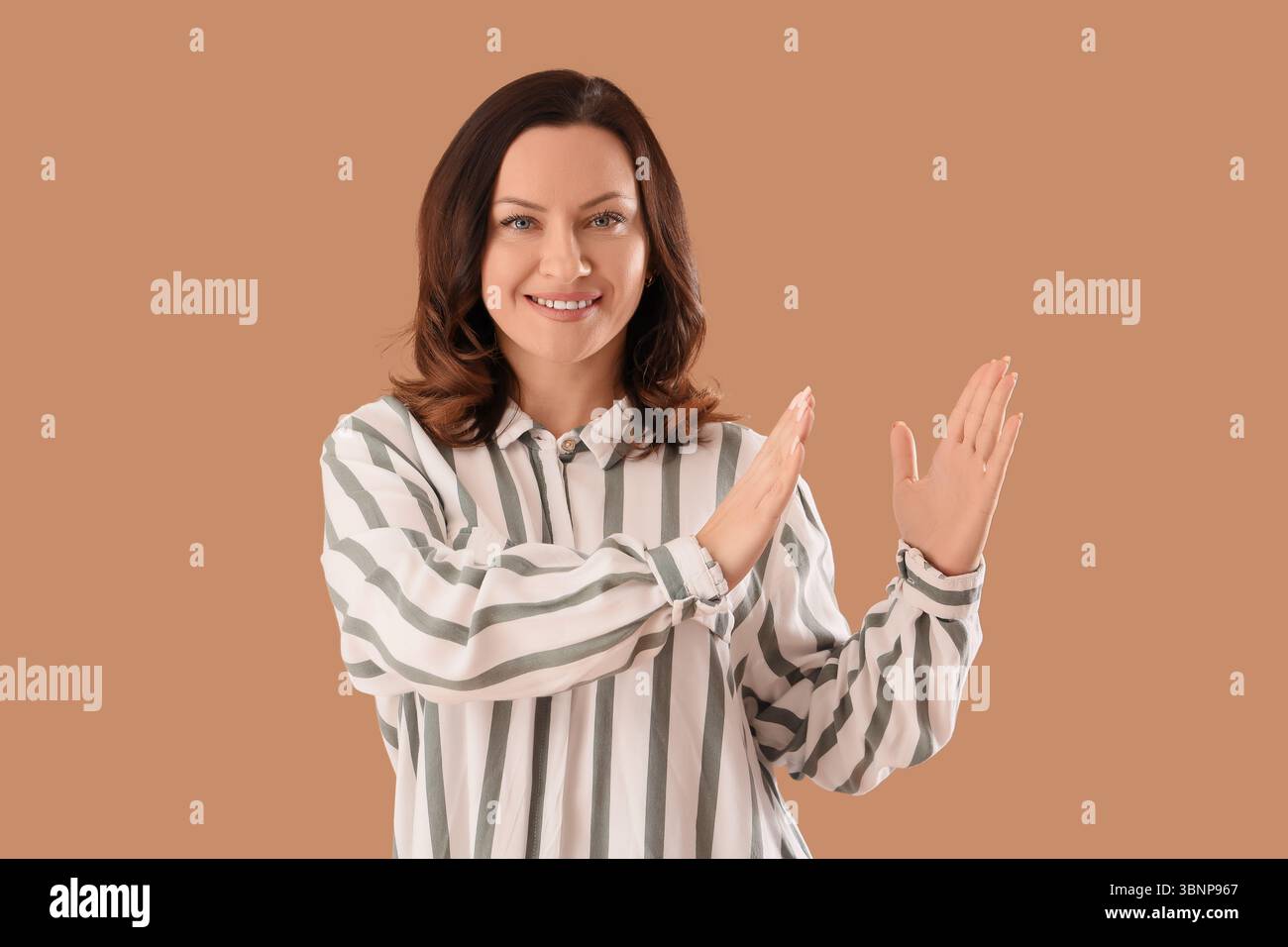 Beautiful happy mature woman clapping hands on brown background Stock Photo