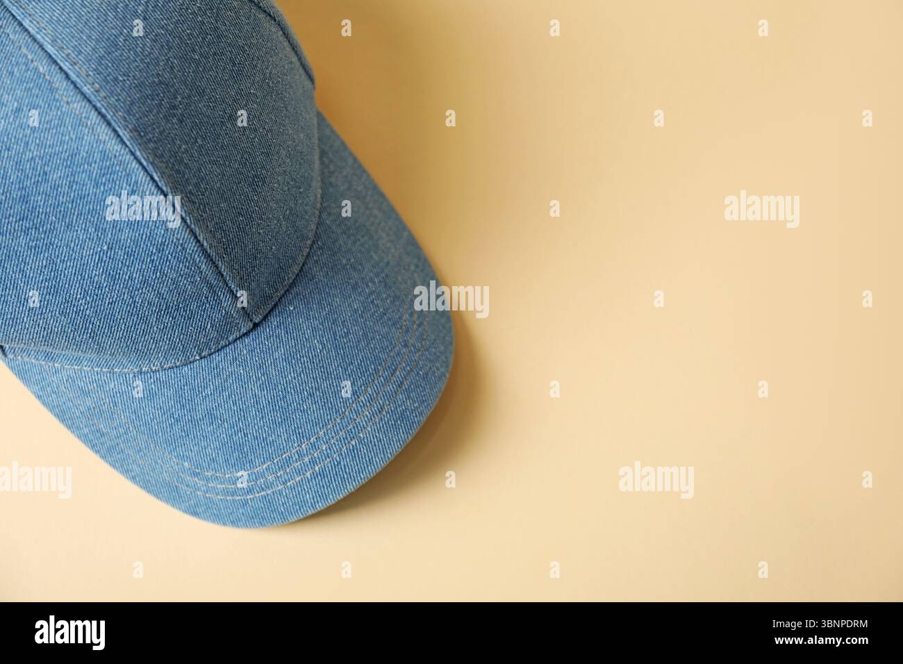 Denim baseball hat on beige background, top view. Space for text Stock Photo