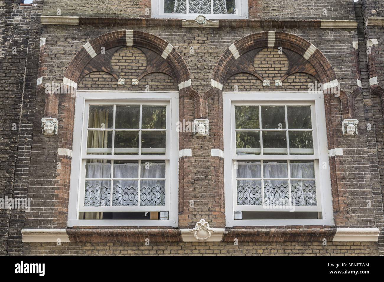 Traditional Dutch white lace curtains behind two ancient windows ...