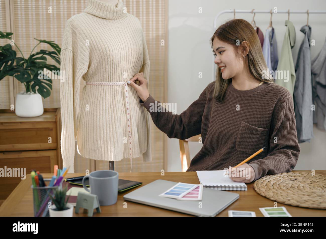Asian Woman Fashion Designer Stylish Artist or creative designer drawing on sketch book with new project design working in studio Stock Photo