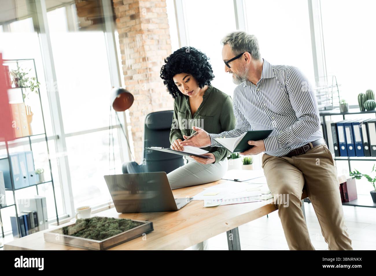 Two diverse business professionals collaborating on a project in a ...