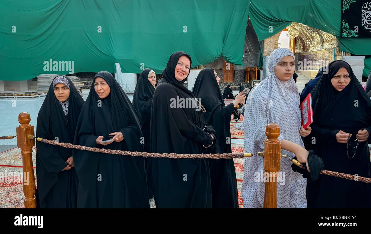 A group of tourists, dressed modestly, enjoy their visit to a significant cultural site in Iraq. Stock Photo