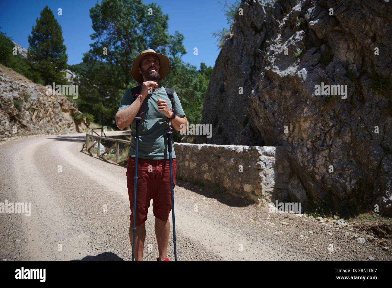 Man in hiking attire standing on a mountain trail, equipped with ...
