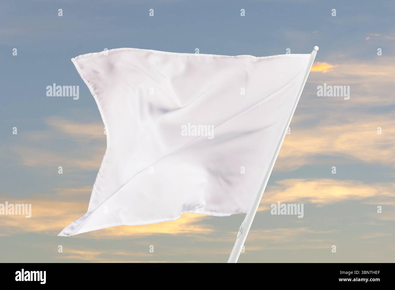 Blank white flag fluttering under sunlight, great for communication themes, clean compositions, or neutral graphic and marketing purposes Stock Photo