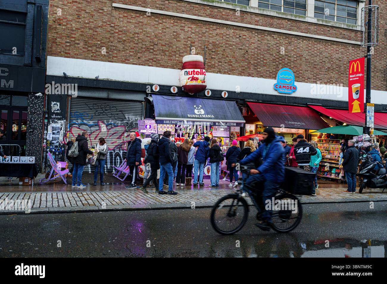 United Kingdom, London, 11 Dec 2024. Crowds walk past food stalls and the iconic Electric Ballroom music venue in Camden Town on a rainy afternoon. Stock Photo